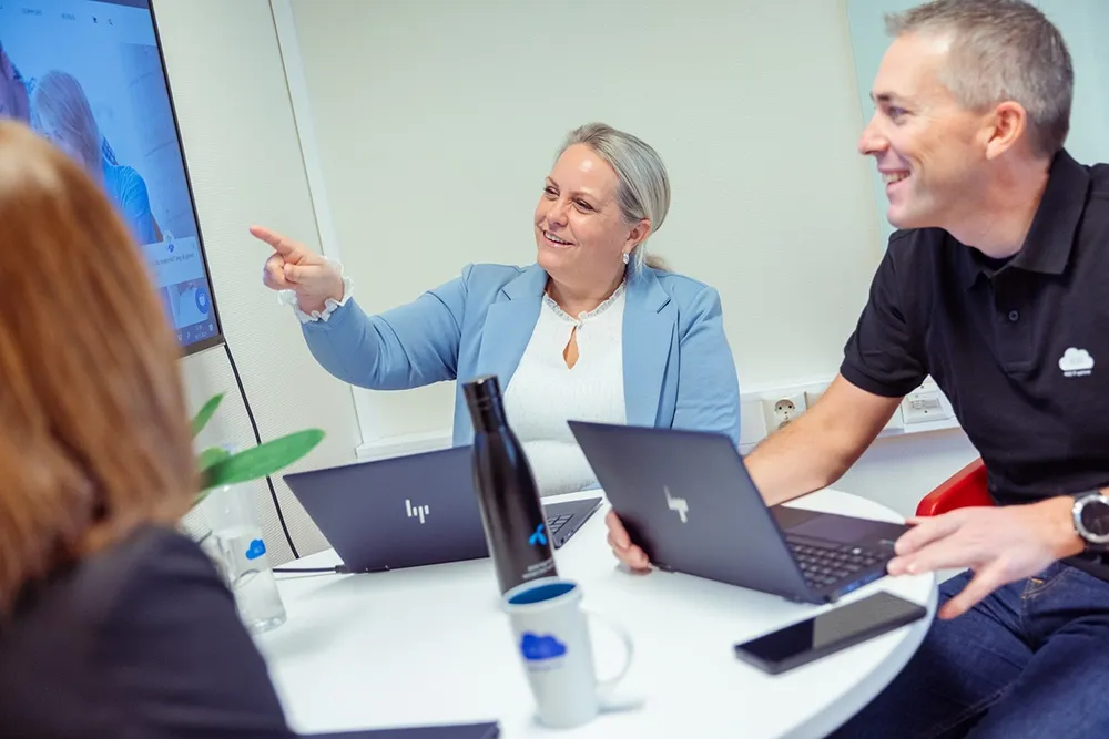 Smilende mennesker med HP pc i møte