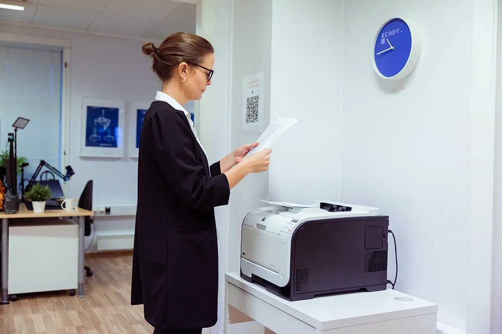 En person som henter printet ark fra printer - Printix cloud print